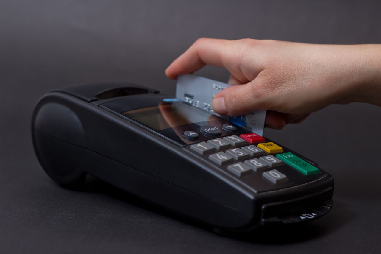 Hand Swiping Credit Card In Store. Female hands with credit card and bank terminal. Color image of a POS and credit cards Hand Swiping Credit Card In Store. Female hands with credit card and bank terminal. Color image of a POS and credit cards.